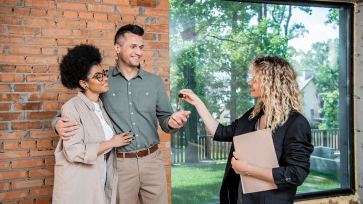 A couple receives the keys to their house from a real estate agent.